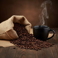 Dark roasted coffee beans spilling from burlap sack beside a steaming black coffee cup