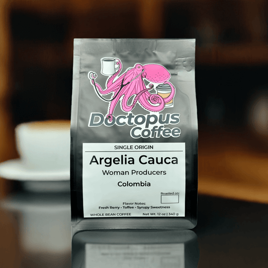 Doctopus Coffee's Argelia Cauca bag staged with coffee cup in background, showing pink octopus logo and Single Origin label on glossy black packaging