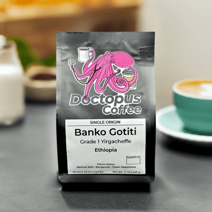 Doctopus Coffee's Banko Gotiti Ethiopian coffee bag displayed in cafe setting with latte cup and saucer in soft focus background