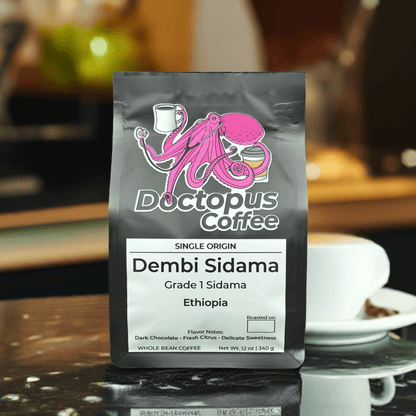 Doctopus Coffee's Dembi Sidama Ethiopian coffee bag displayed on marble counter with coffee cup and plant in soft-focus background