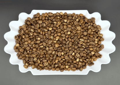 Light roasted Ethiopian coffee beans from Banko Gotiti displayed in white scalloped dish, showing uniform roast color and characteristic split crease